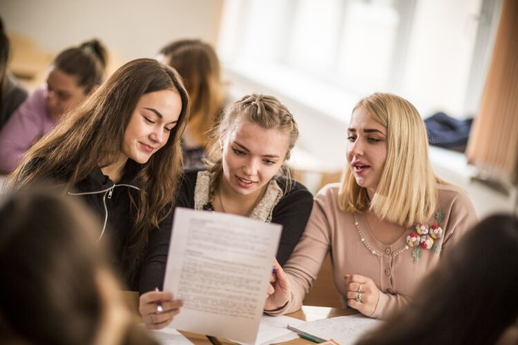 Three secondary learners working together in a classroom and smiling