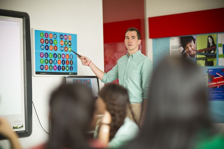 Teacher in Vietnam stands in front of phonemic chart