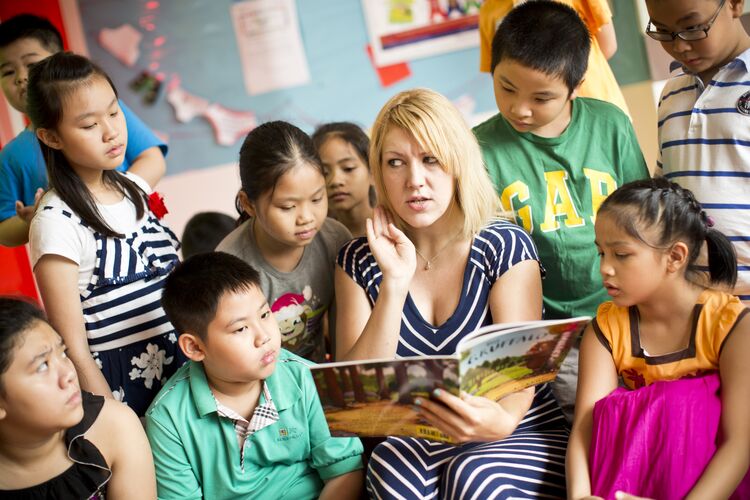 Teacher with a storybook surrounded by young learners