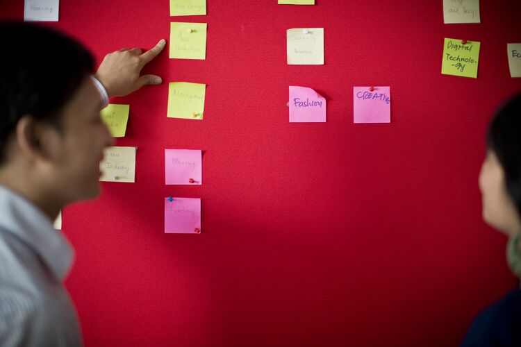 Two people discussing post-its on a board