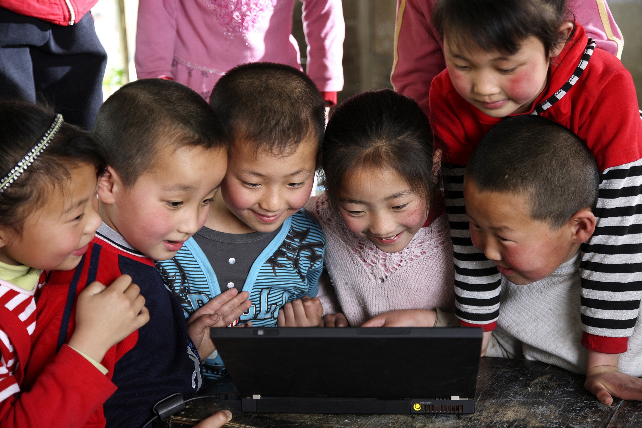 A group of Chinese students and teacher looking at a tablet